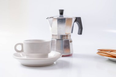 Kahve makinesi, beyaz arka planda beyaz kahvaltı fincanı ve kurabiyeler.