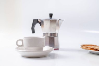 Kahve makinesi, beyaz arka planda beyaz kahvaltı fincanı ve kurabiyeler.