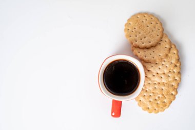 Beyaz arka planda kurabiyeler olan kırmızı kahve fincanı