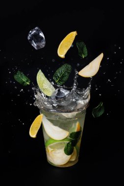 Buz küpleri limon, limon ve naneli limonata bardağına sıçrıyor.