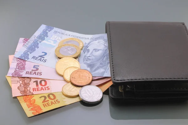 Brazilian Money, Currency of Brazil, Real, Reais, various bills and coins inside a wallet, close-up on dark background. Cash money