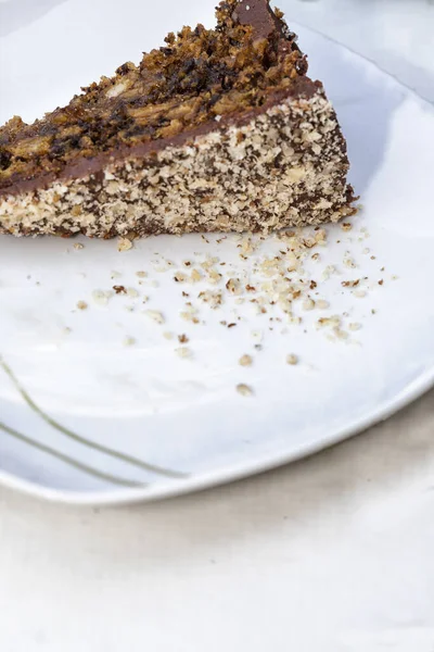 白いプレートの上に茶色の肌 チョコレートケーキの景色を閉じます チョコレートパン粉が皿の上に見える — ストック写真