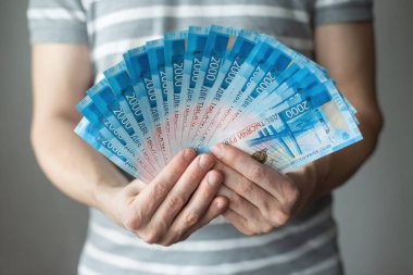 2000 Ruble 'lik Rus para banknotları erkeklerin elinde şeritli beyaz ve gri bir gömleğin arka planında