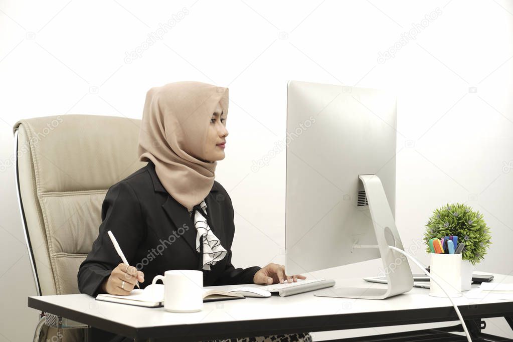 Portrait of casual businesswoman in sweater sitting at her workplace in office