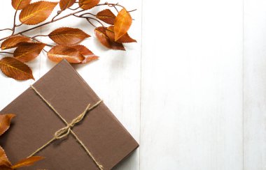 Sonbahar kompozisyonu. Hediye, sonbahar yaprakları, tarçın çubukları, ahşap beyaz arka planda anason yıldızı. Düz konum, üst görünüm, kopyalama alanı