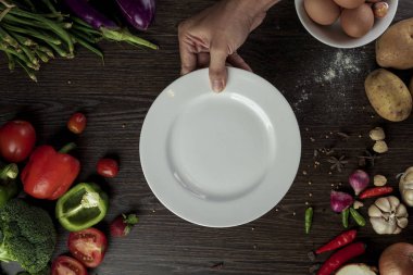 Taze organik sebze ve boş beyaz plaka etrafında lezzetli vejetaryen yemek için baharat maddeler, üst görünümü. Sağlıklı veya diyet gıda kavramı.