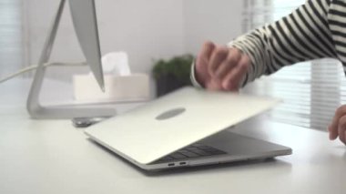 Genç bir adam bir dizüstü bilgisayar açtı ve onu bir mendille temizledi.