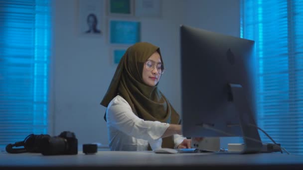 美しいイスラム教徒のアジア人は 現代的なインテリアデザインのコワーキングスペースで夜に自宅から仕事をしていたときに呼び出しにあった — ストック動画