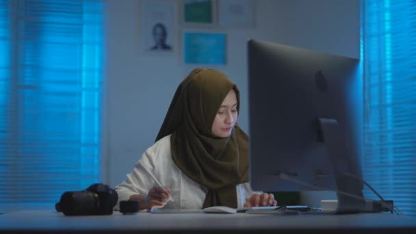 아름다운 아시아 모슬렘의 부드러운 초점어두운 스카프를 착용하고 집에서 일하며 즐겁게 — 비디오