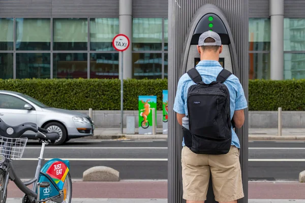 Um homem em uma estação de compartilhamento de bicicletas, pagando com seu cartão para alugar uma bicicleta em Dublin, Irlanda — Fotografia de Stock