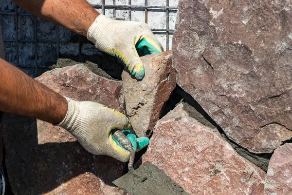 Bouwer - metselaar handen plaatsen stenen op een muur met behulp van een spatel met cement, buiten — Stockfoto