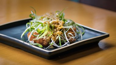 Kore usulü kızarmış tavuk ve üstüne yeşil soğan dilimlenmiş siyah bir tabak, Busan, Güney Kore