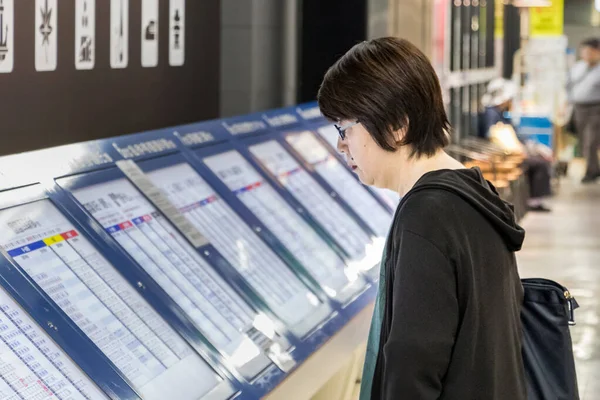 Weibliche japanische Passagierin beim Blick auf den Fahrplan im Buszentrum von Hiroshima, Japan. — Stockfoto