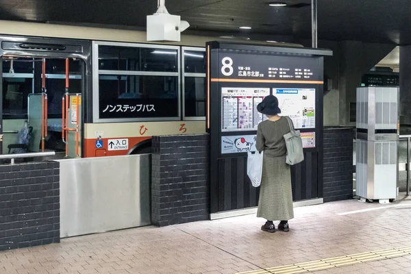 Weibliche japanische Passagierin beim Blick auf den Fahrplan im Buszentrum von Hiroshima, Japan. — Stockfoto