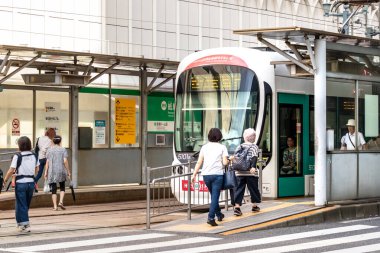 Japon yolcular Hiroşima 'daki Kamiyacho-nishi tramvay istasyonundan trene biniyorlar..