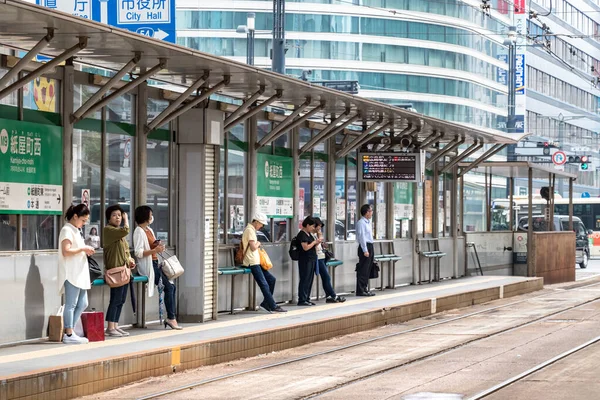 Japanische Fahrgäste warten an der Straßenbahnhaltestelle Kamiyacho-nishi in Hiroshima auf die Straßenbahn. — Stockfoto