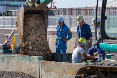 Japon inşaatçılar Kanazawa, Japonya 'da bir kazıcı kullanarak sokaklarda çalışıyorlar.