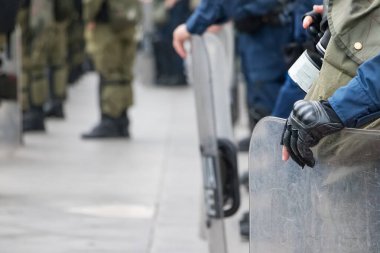 Erkek çevik kuvvet polisi kalkanını eliyle tutuyor..