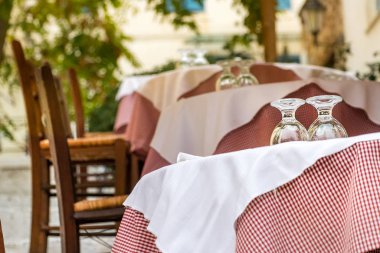 Atina 'nın Plaka kentindeki bir Yunan tavernasında tahta sandalyeler ve gözlüklü masa.