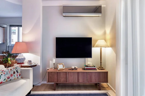 Armário de madeira com tv plana e lâmpadas em uma pequena sala de estar . — Fotografia de Stock