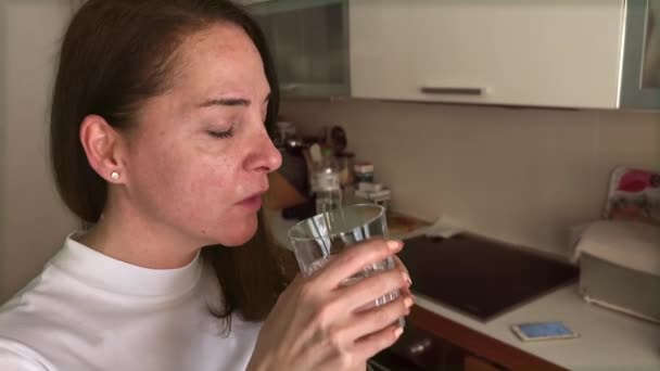 Egy érett nő, 48 éves, tablettákat szed egy pohár vízzel, bent.. — Stock videók