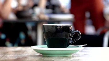 Tabaklı bir kahve fincanı, açık havada bir kahve dükkanında. Kahve molası