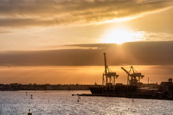 Silhuetas de navios e guindastes no porto de Melbourn ao pôr-do-sol, Austrália — Fotografia de Stock