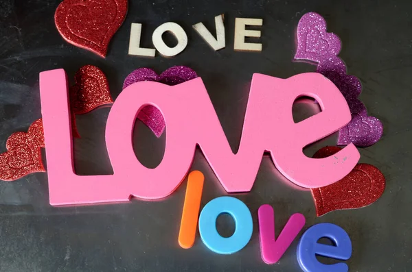 Love spelled out in wooden and plastic letters, glittery hearts
