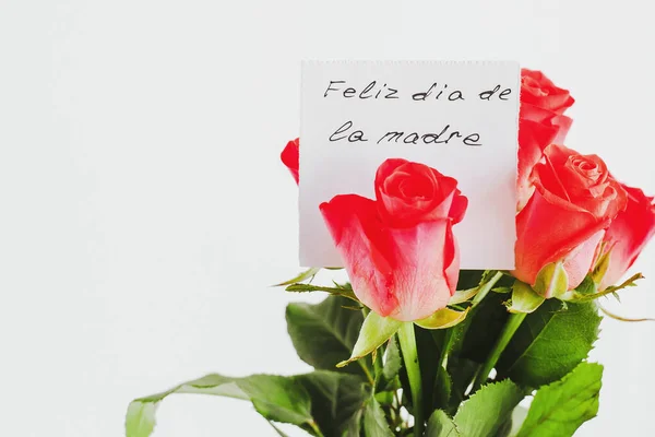 Mother\'s day greeting card on white background: Bouquet of small roses and a handwritten gift card with the inscription Happy Mother\'s Day in Spanish