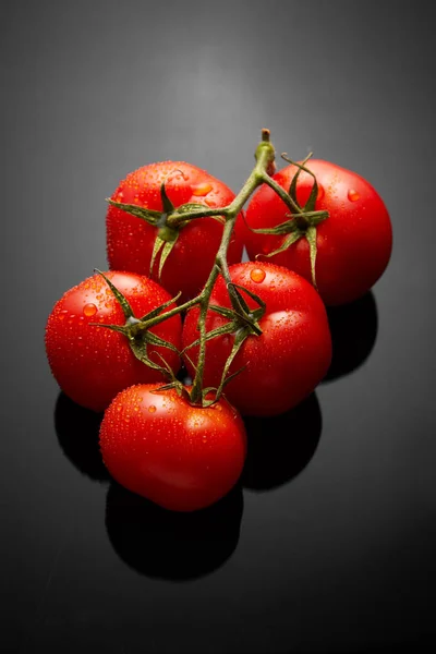 Imagem do molho de tomates frescos no fundo preto com reflexão e gotas de água — Fotografia de Stock