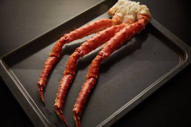 Image of fresh crab phalanges on oven-tray over dark background with copyspace clipart