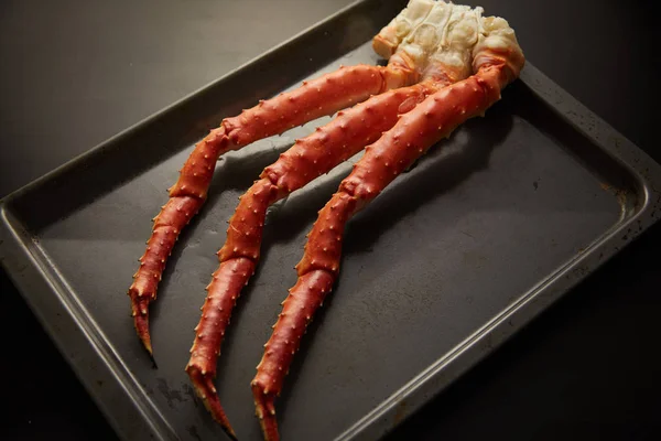 Image of fresh crab phalanges on oven-tray over dark background with copyspace — 스톡 사진