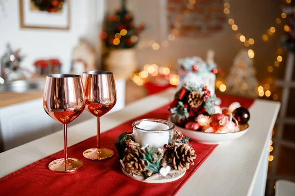 Beautiful holiday decorated kitchen with Christmas tree and bright lights , holiday glasses and christmas composition on the main plan, blur background