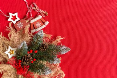 Kırmızı arka planda Noel süslemeleri ve metin için fotokopi alanı olan bir fiş dalı. Noel veya Yeni Yıl arkaplanı