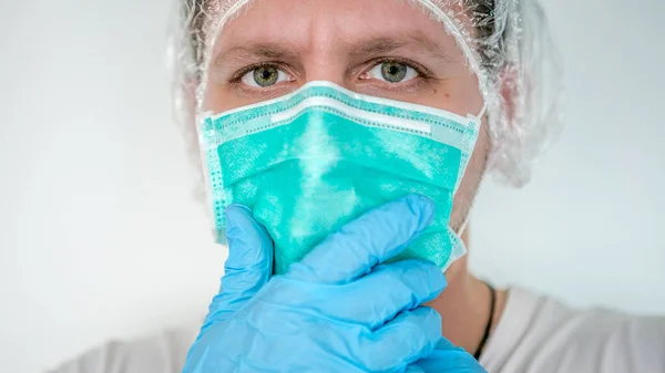 Hands with blue gloves putting on a medical face mask to protect the upper respiratory tract. Man hand puts on a protective facial mask against virus and infection diseases. Coronavirus 2019-nCoV