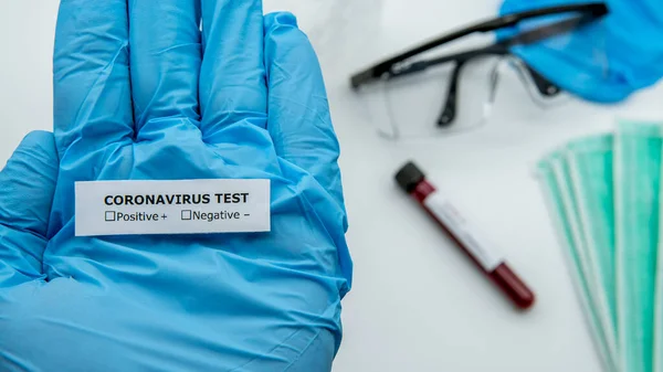 Scientist with blue gloves hold the identifier sticker for test tube with infected blood sample for COVID-19, novel coronavirus found in Wuhan, China. Vaccine research for the virus 2019-nCoV.