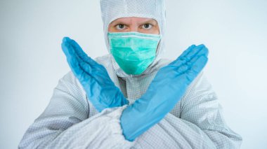 Beyaz erkek doktor koruyucu giysi ve maske takıyor, dur işareti yapıyor, hayır işareti veriyor. Virüs hastalığını reddediyorsan, kapat. Beyaz arka planda izole edilmiş. Tıbbi ve sağlık hizmetleri kavramı.