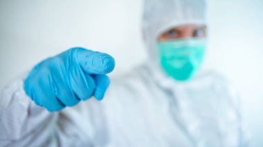 Erkek doktor işaret ediyor. Koruyucu takım elbiseli ve maskeli beyaz bir adam, beyaz bir arka planda izole edilmiş sağlık ve sağlık hizmetleri konsepti ile sinyal veriyor. Çin koronavirüsü salgını.