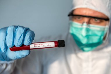 COVID-19 'un iyileşmesine yardımcı olmak için sağlık hizmeti. Bilim adamları koronavirüs negatif kan örneği testine karşı koruyucu giysi ve ameliyat eldiveni giyerler. Bilim adamı doktor biyolojik tehlike koruma kıyafeti