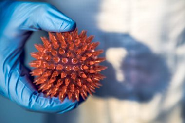 Corona virüsü modeli olan bir tıp doktoru. Korunma giysisinde Coronavirus var. MERS-Cov virüsünün soyut molekülü. Tıbbi ve sağlık konsepti, biyolojik tehlike.