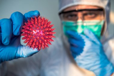 Kafkasyalı bir doktor Coronavirus kırmızı hastalığı taşıyor. Koruyucu giysi giymiş erkek bilim adamı ve COVID19 molekülü. Tıbbi ve sağlık konsepti, biyolojik tehlike.