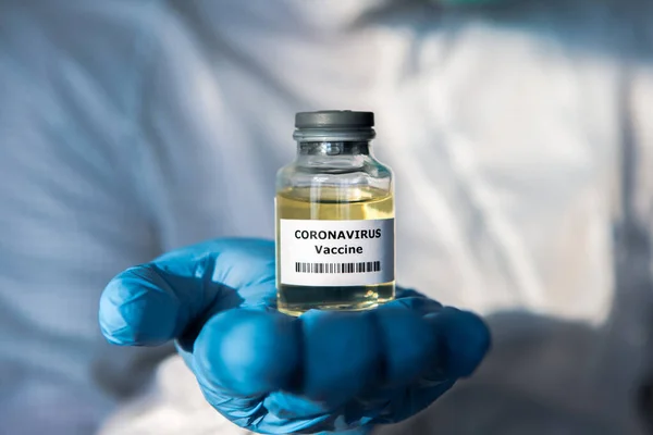Scientific with protective suit holds a vaccine for coronavirus. Vaccination for COVID-19. 2019-nCoV found in Wuhan China. Epidemic virus outbreak concept. Medical and health care concept.