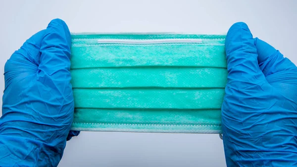 Наука Носит Голубые Перчатки Держит Зеленую Медицинскую Маску Белом Фоне — стоковое фото