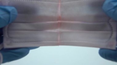4K, mavi eldivenli yakın çekim eller kameraya solunum maskesi takın. Doktor tıbbi maske takıyor. Grip, grip, virüs, bademcik iltihabı, akut solunum hastalığı, karantina, salgın konsepti Dan