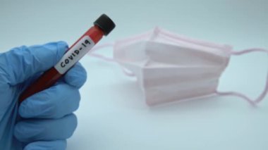 4K, yüz maskesi ve COVID-19 için enfekte kan örneği içeren test tüpü, Wuhan, Çin 'de bulunan yeni bir coronavirüs. Koruma için mavi eldivenli bilim adamı. 2019-nCoV-Dan virüsü için aşı araştırması