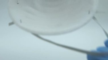 4K, mavi eldivenli yakın çekim eller kameraya solunum maskesi takın. Doktor tıbbi maske takıyor. Grip, grip, virüs, bademcik iltihabı, akut solunum hastalığı, karantina, salgın konsepti Dan