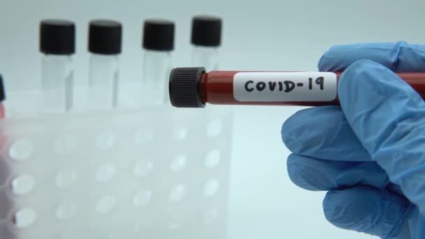带有Covid 19感染血样的试管 在中国武汉发现新的头孢病毒 带着蓝色防护手套的科学家 2019 Ncov Dan病毒疫苗研究 — 图库视频影像