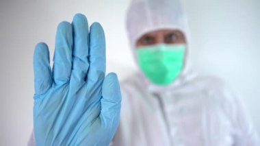 4K, koruyucu giysi ve maske takan beyaz erkek doktor dur işareti yapıp 