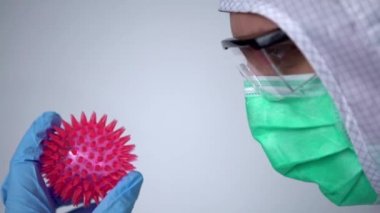 4K, Coronavirus kırmızı hastalığı olan beyaz bir doktor laboratuarda. Koruyucu giysi giymiş erkek bilim adamı ve COVID19 molekülü. Tıbbi ve sağlık konsepti, biyolojik tehlike.