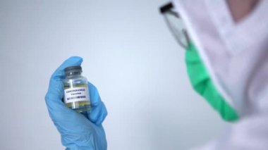 4K, koruyucu giysi giymiş koruyucu bir erkek, aşı şişesi koronavirüsü, Aşı kovid-19 enjeksiyon hastalığı olan beyaz bir adam. Önleme bağışıklığı hastalığı - Dan